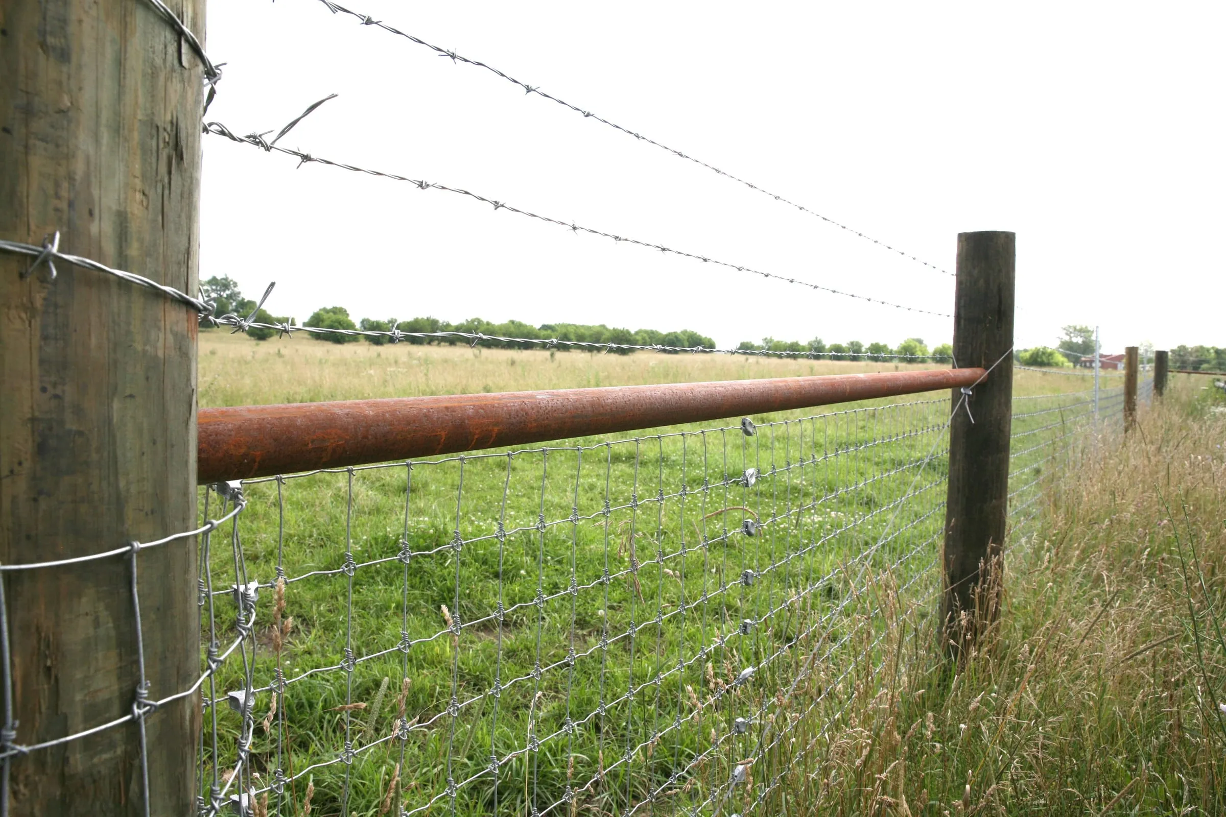Woven wire and barbed wire on wood posts