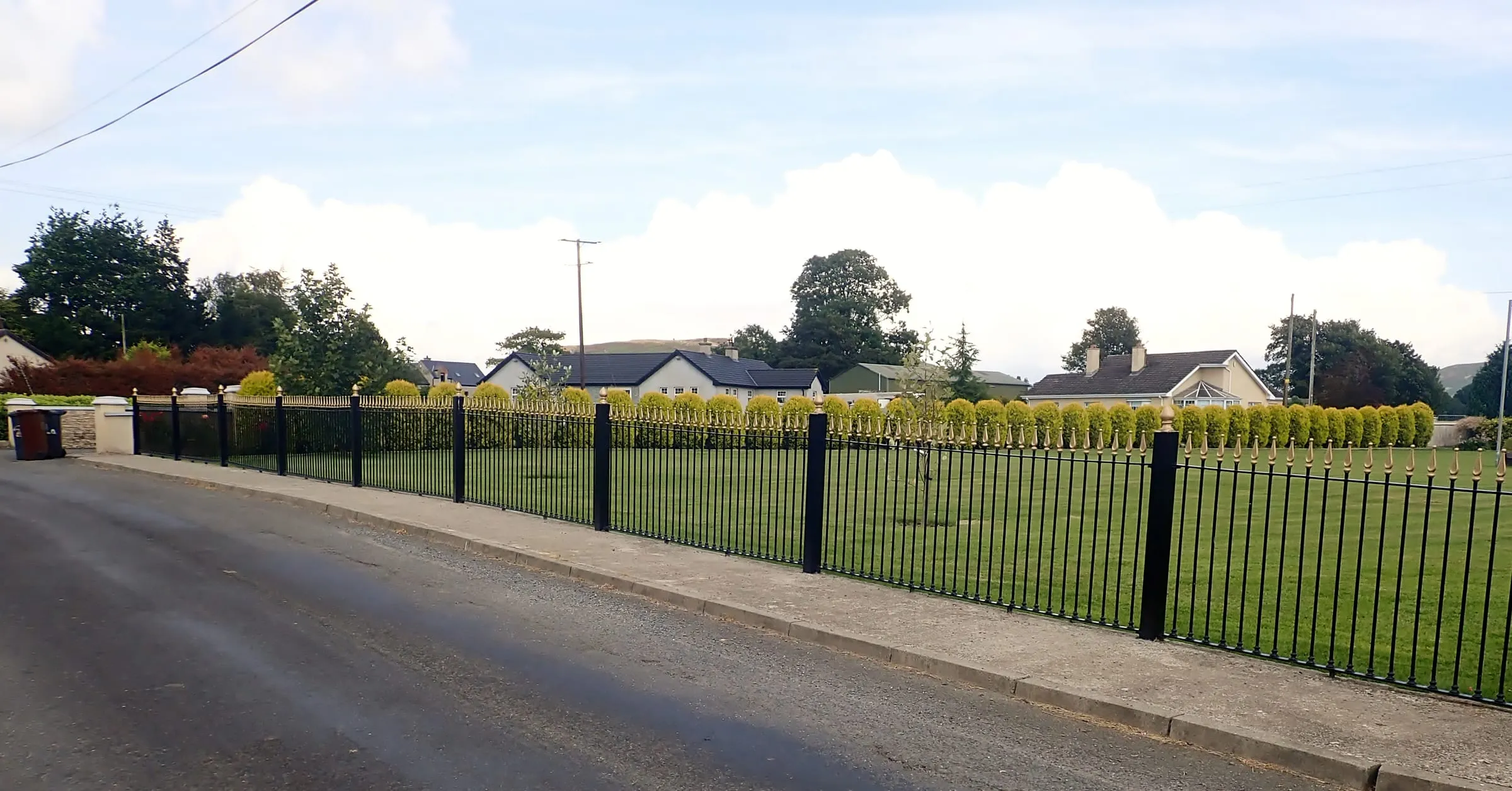 A black metal picket fence along a lawn